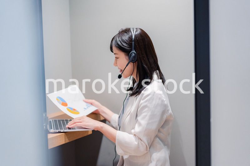 シェアオフィスの個室ブースでリモート会議をする女性