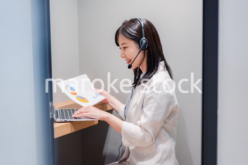 シェアオフィスの個室ブースでリモート会議をする女性