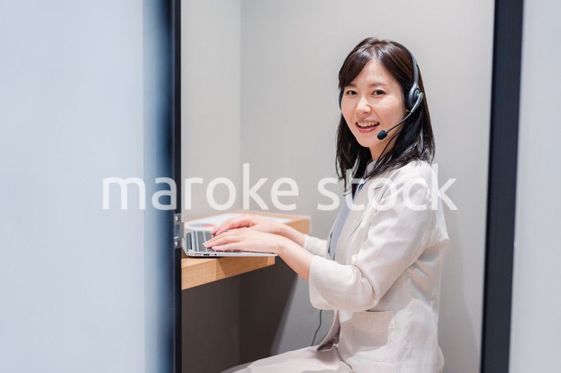 シェアオフィスの個室ブースでリモート会議をする女性