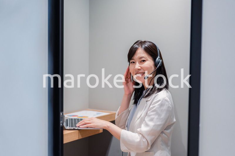 シェアオフィスの個室ブースでリモート会議をする女性