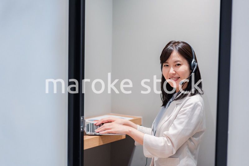 シェアオフィスの個室ブースでリモート会議をする女性