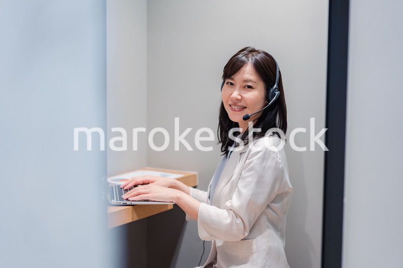 シェアオフィスの個室ブースでリモート会議をする女性