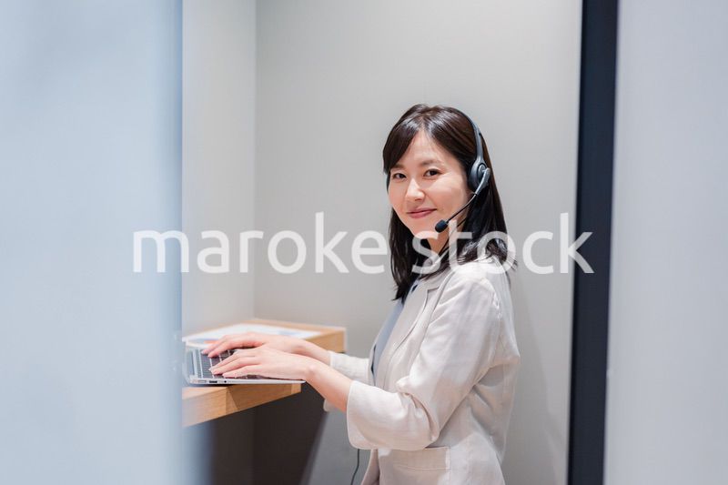 シェアオフィスの個室ブースでリモート会議をする女性