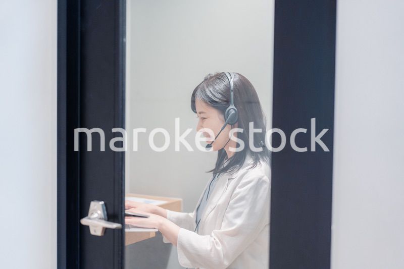シェアオフィスの個室ブースでリモート会議をする女性
