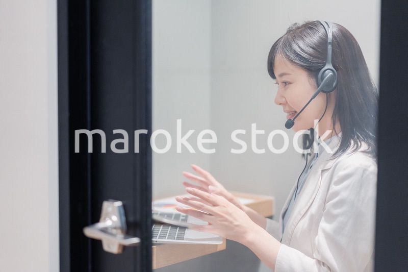 シェアオフィスの個室ブースでリモート会議をする女性