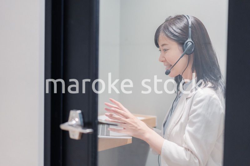 シェアオフィスの個室ブースでリモート会議をする女性