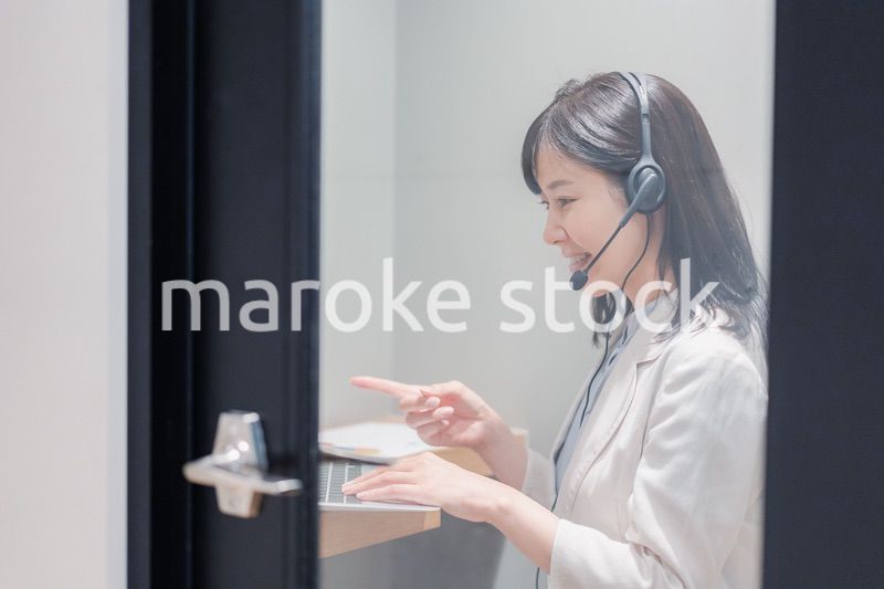 シェアオフィスの個室ブースでリモート会議をする女性