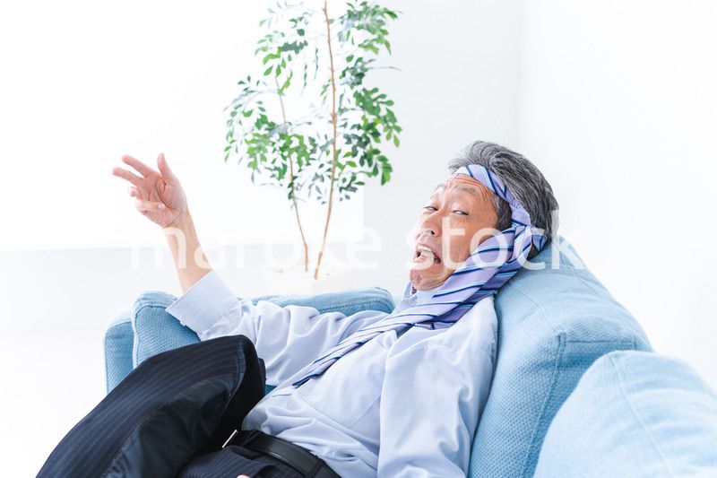 酔っ払ってソファーで寝るサラリーマンの男性