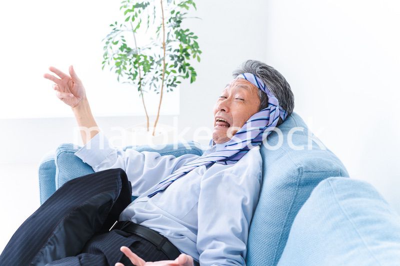 酔っ払ってソファーで寝るサラリーマンの男性