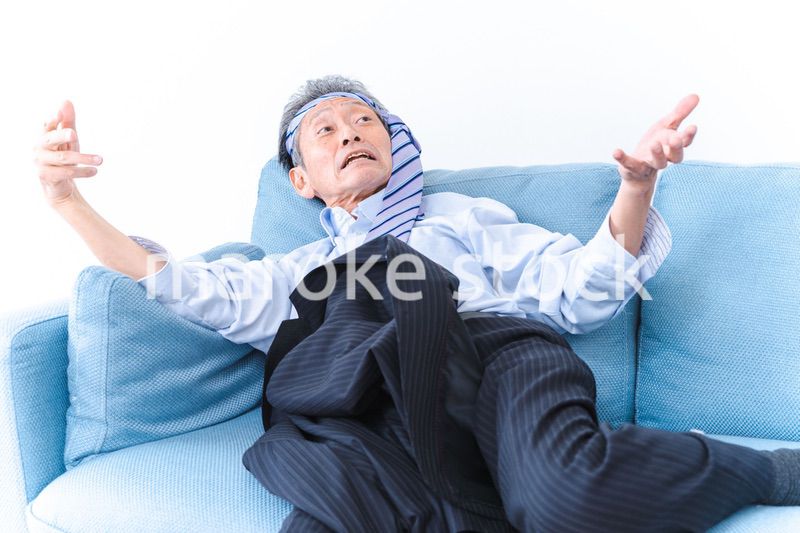 酔っ払ってソファーで寝るサラリーマンの男性