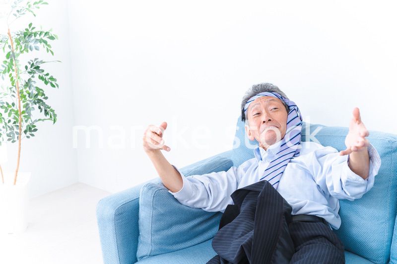 酔っ払ってソファーで寝るサラリーマンの男性