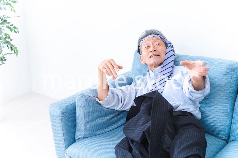 酔っ払ってソファーで寝るサラリーマンの男性