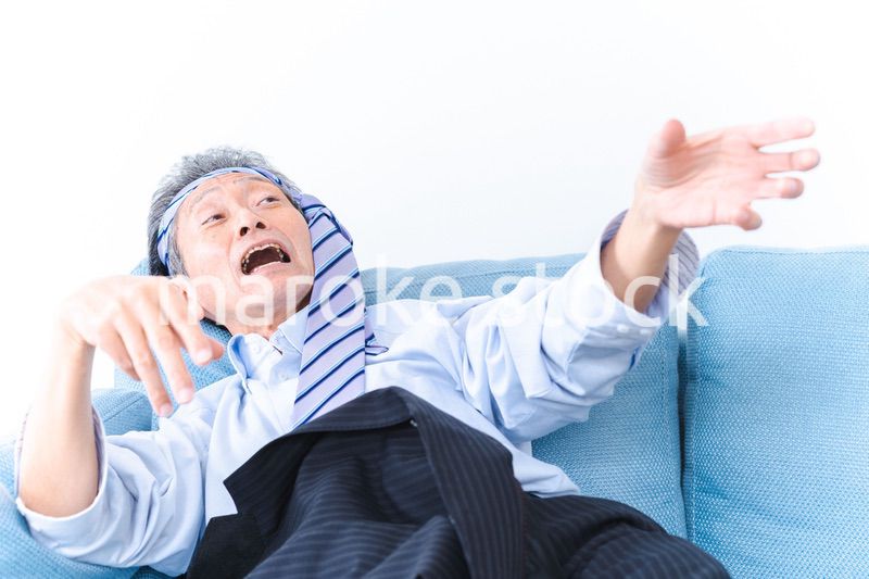 酔っ払ってソファーで寝るサラリーマンの男性