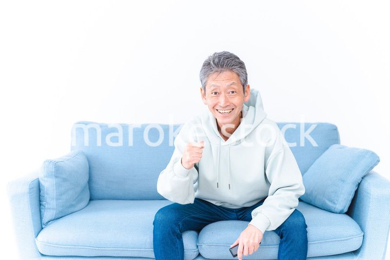 自宅のテレビでスポーツ観戦をする高齢の男性