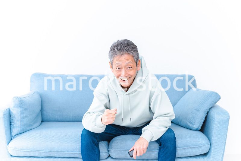 自宅のテレビでスポーツ観戦をする高齢の男性