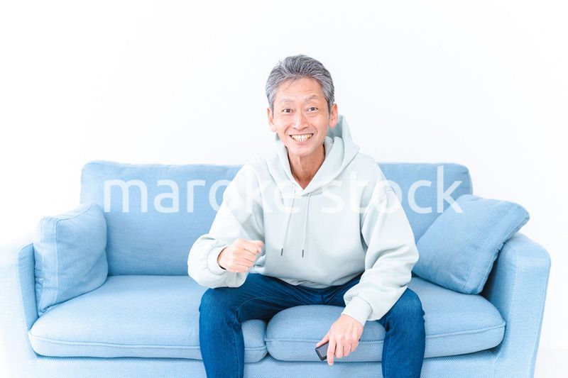 自宅のテレビでスポーツ観戦をする高齢の男性