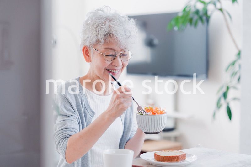 笑顔で朝食を食べるシニアの女性