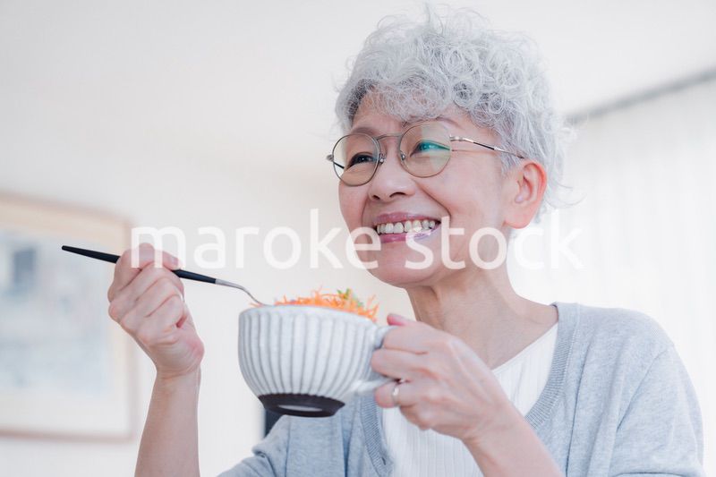 笑顔で朝食を食べるシニアの女性