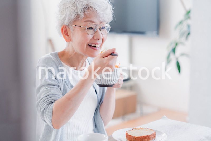 笑顔で朝食を食べるシニアの女性