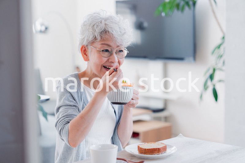笑顔で朝食を食べるシニアの女性