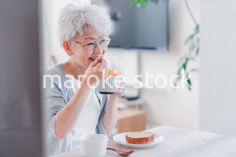 笑顔で朝食を食べるシニアの女性