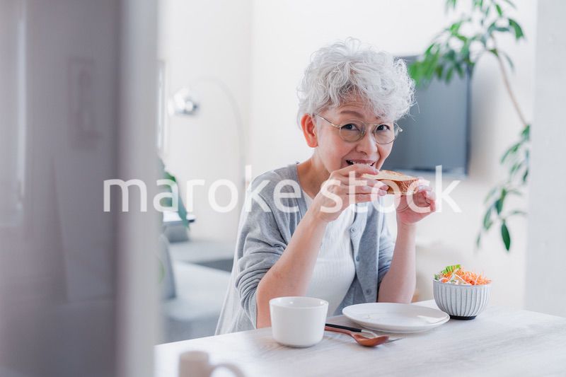 笑顔で朝食を食べるシニアの女性