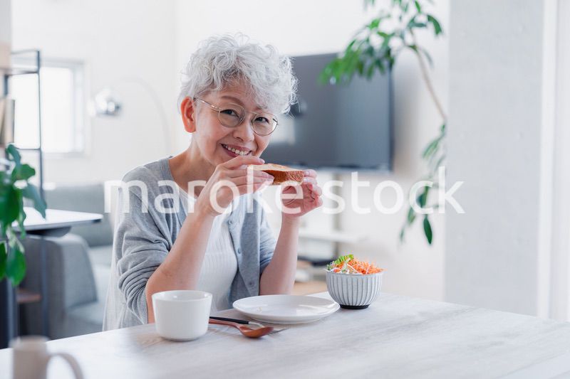 笑顔で朝食を食べるシニアの女性