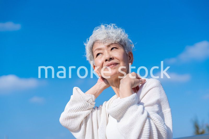 青空の下でストレッチをするシニアの女性