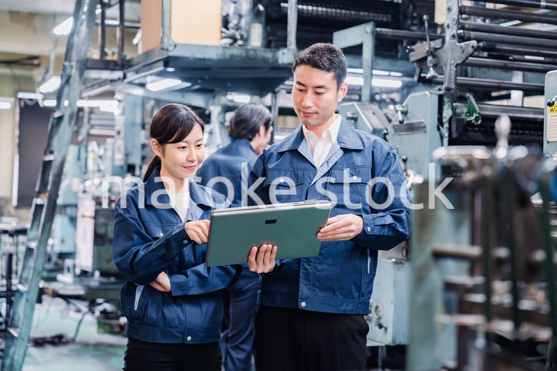 タブレットを見ながら工場で議論をするスタッフ