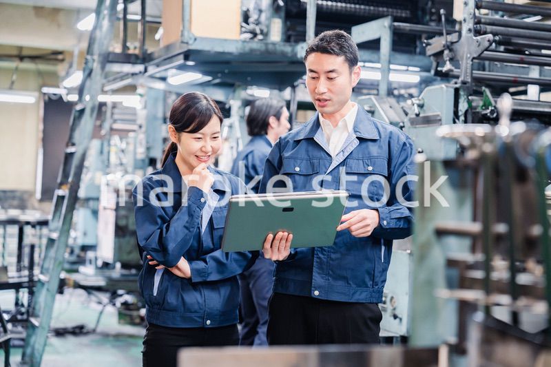 タブレットを見ながら工場で議論をするスタッフ