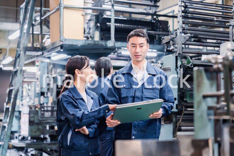 タブレットを見ながら工場で議論をするスタッフ