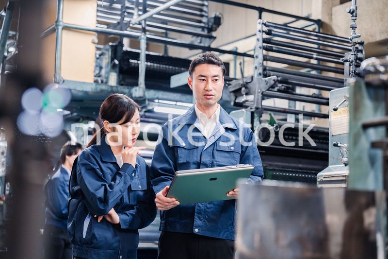 タブレットを見ながら工場で議論をするスタッフ