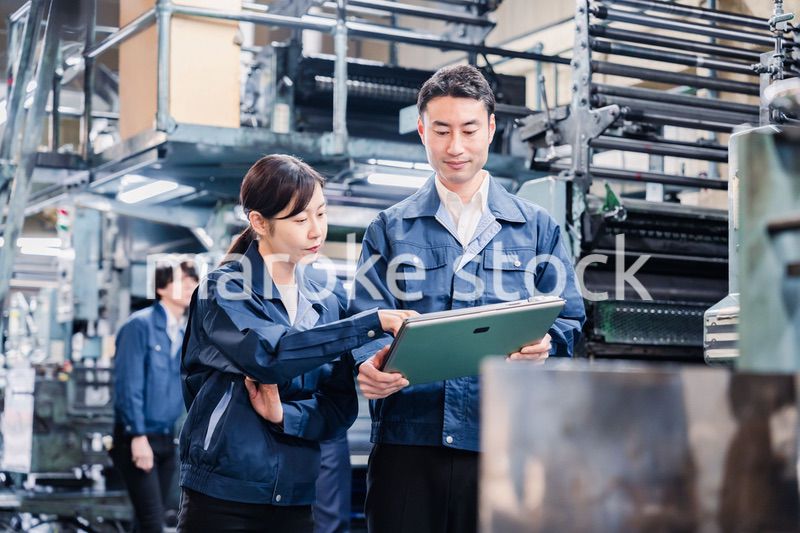 タブレットを見ながら工場で議論をするスタッフ