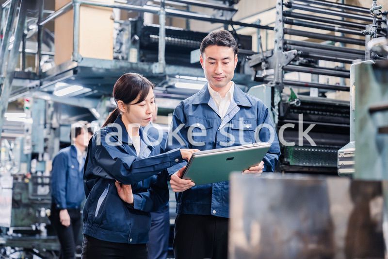 タブレットを見ながら工場で議論をするスタッフ