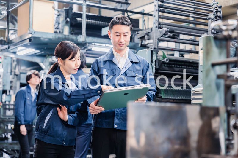 タブレットを見ながら工場で議論をするスタッフ