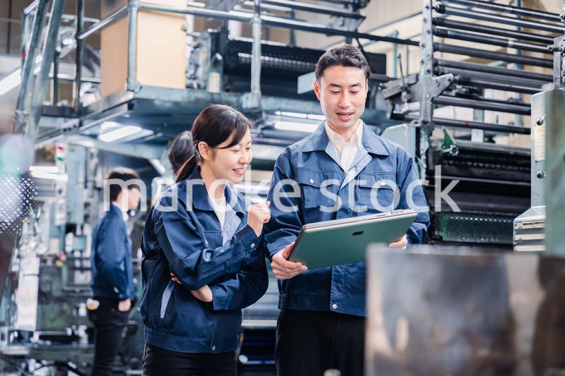 タブレットを見ながら工場で議論をするスタッフ