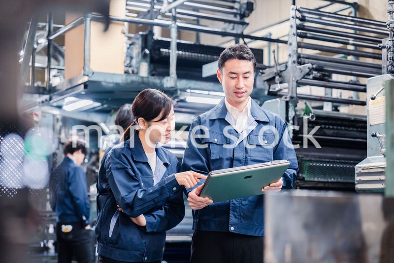 タブレットを見ながら工場で議論をするスタッフ