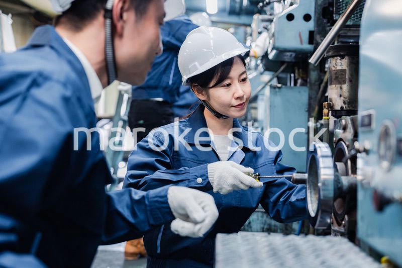 工場で作業を教えてもらう外国人労働者