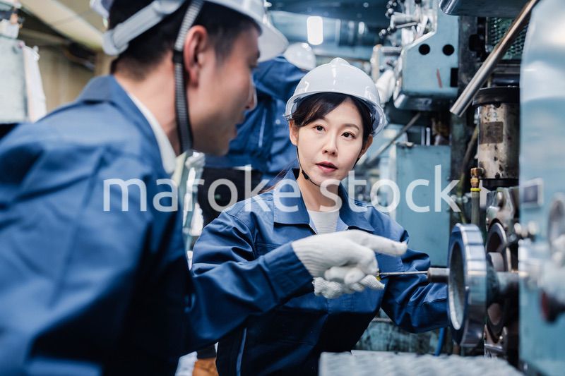 工場で作業を教えてもらう外国人労働者