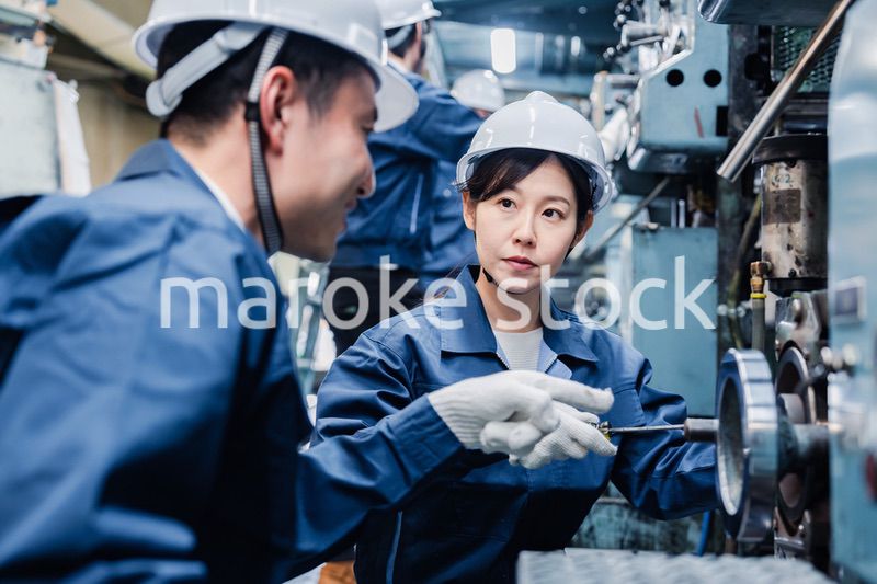 工場で作業を教えてもらう外国人労働者