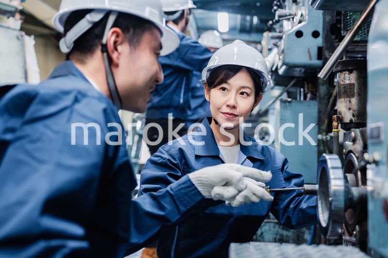 工場で作業を教えてもらう外国人労働者