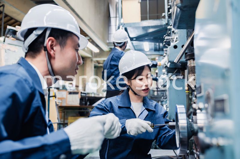 工場で作業を教えてもらう外国人労働者