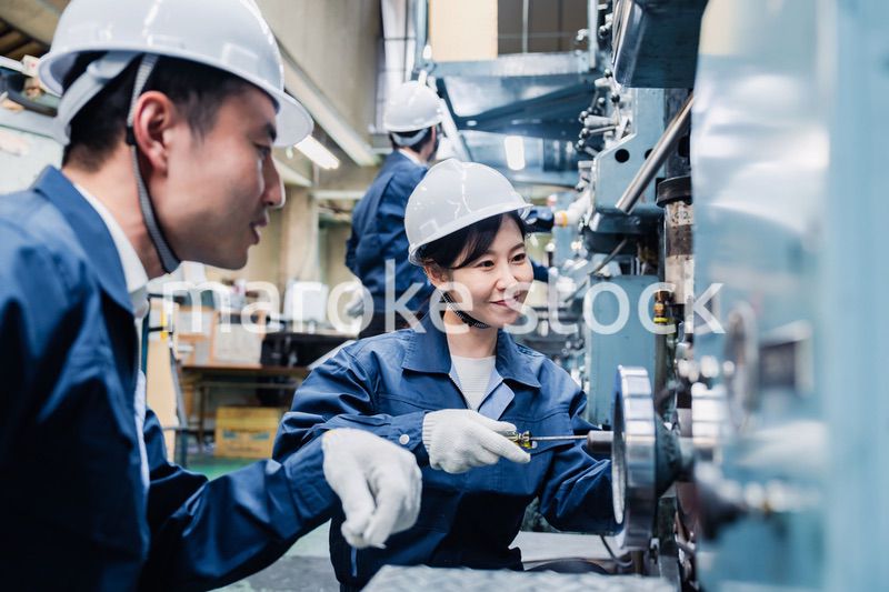 工場で作業を教えてもらう外国人労働者