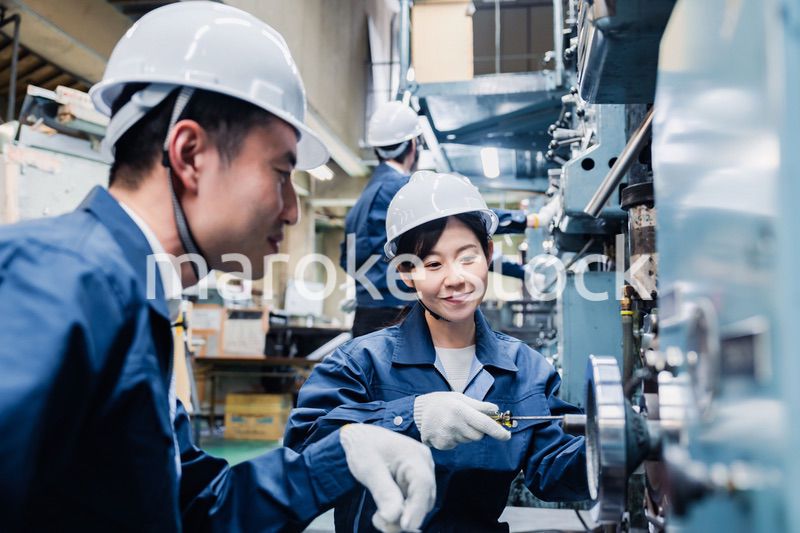 工場で作業を教えてもらう外国人労働者