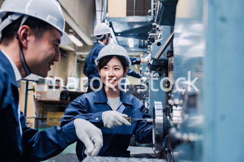 工場で作業を教えてもらう外国人労働者