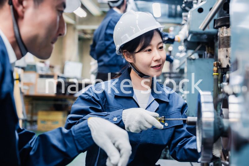 工場で作業を教えてもらう外国人労働者