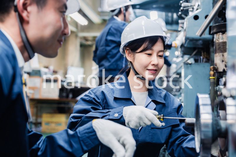 工場で作業を教えてもらう外国人労働者