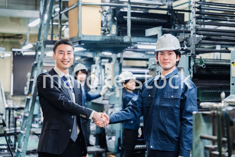 取引先と握手をする工場のスタッフ