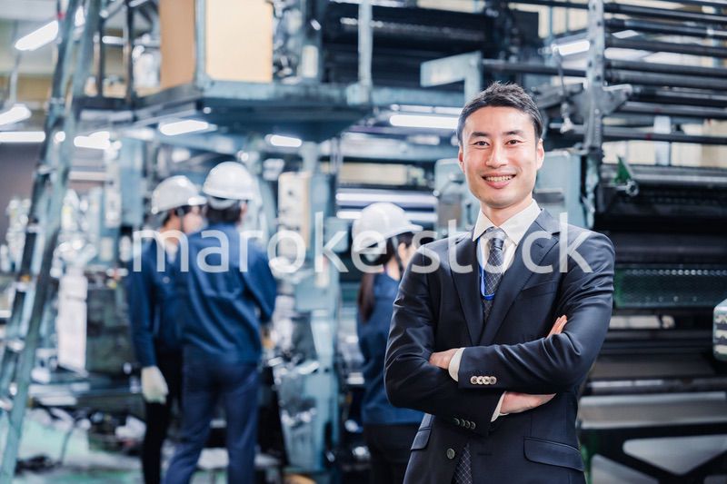 工場で腕を組むホワイトカラーの男性