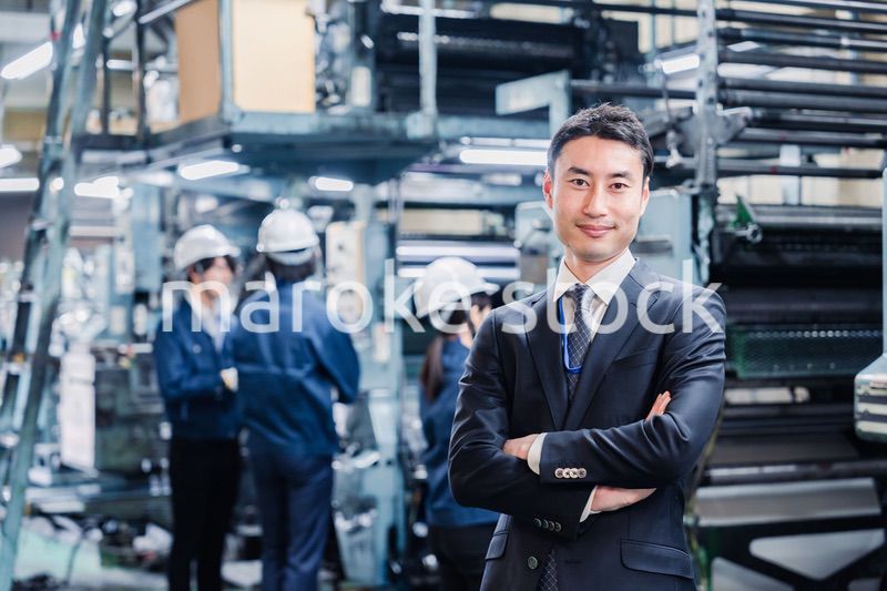 工場で腕を組むホワイトカラーの男性